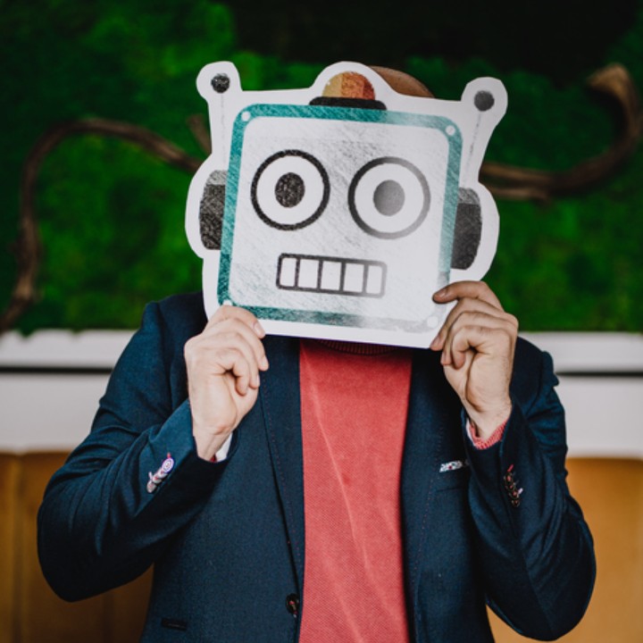 Programista Digibit trzyma emoji robota w miejscu swojej twarzy.